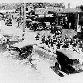 Virtue Motors with a parade band marching on Lakeshore Road, ca 1920